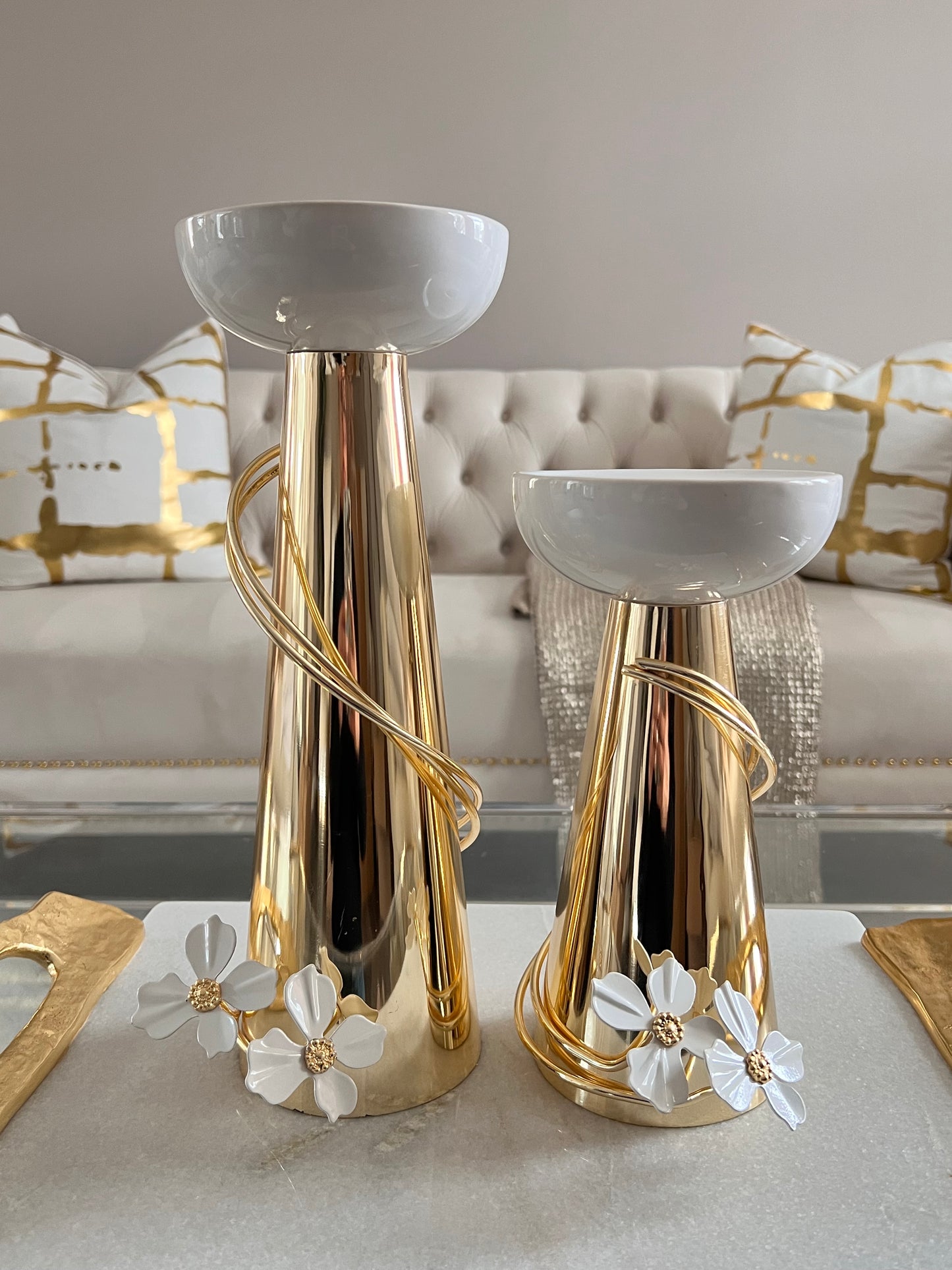 Gold candleholders whit white flower detail.