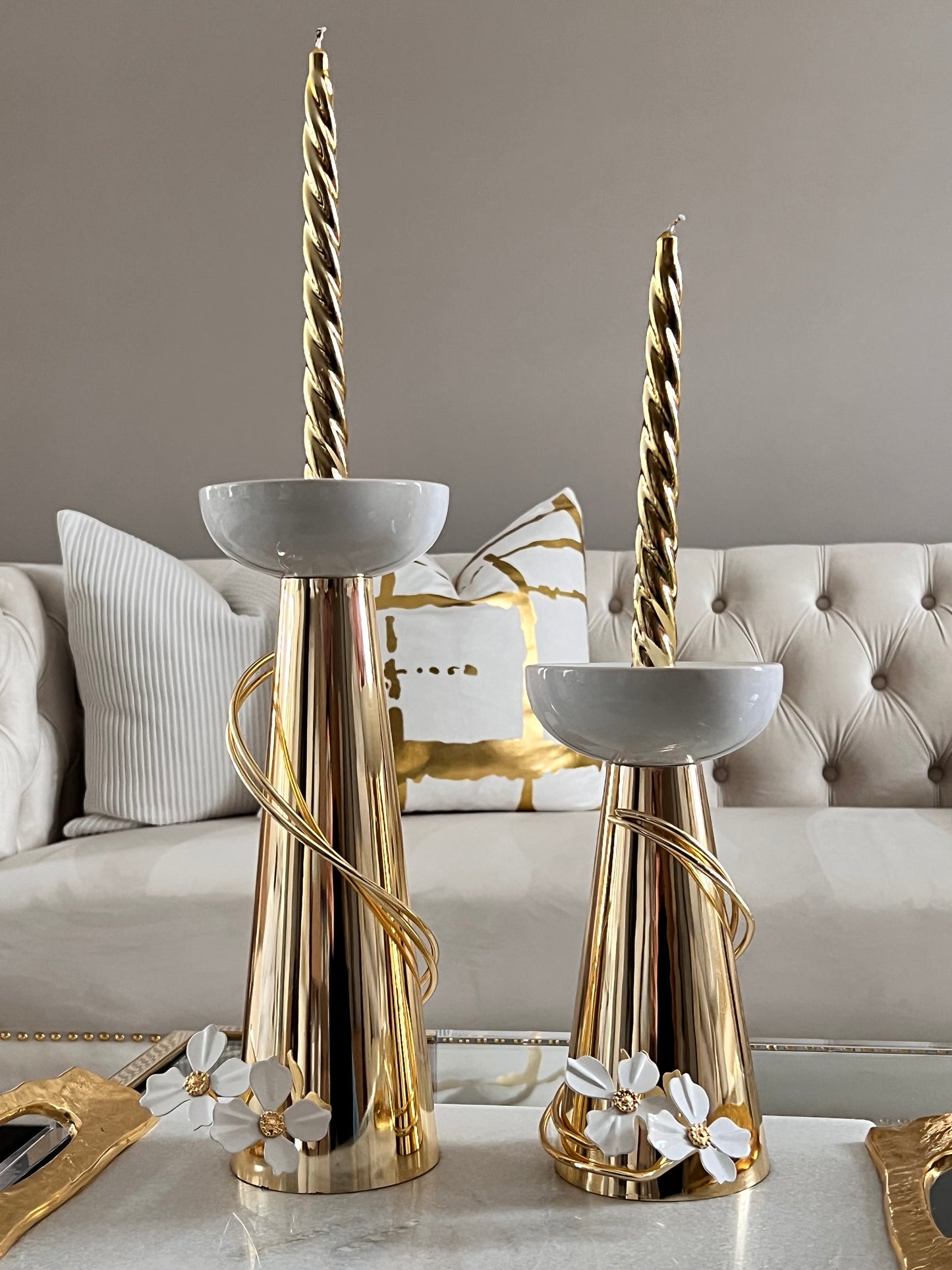 Gold candleholders whit white flower detail.