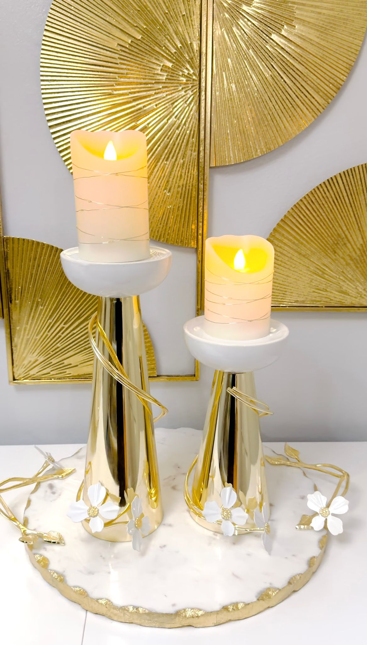 Gold candleholders whit white flower detail.