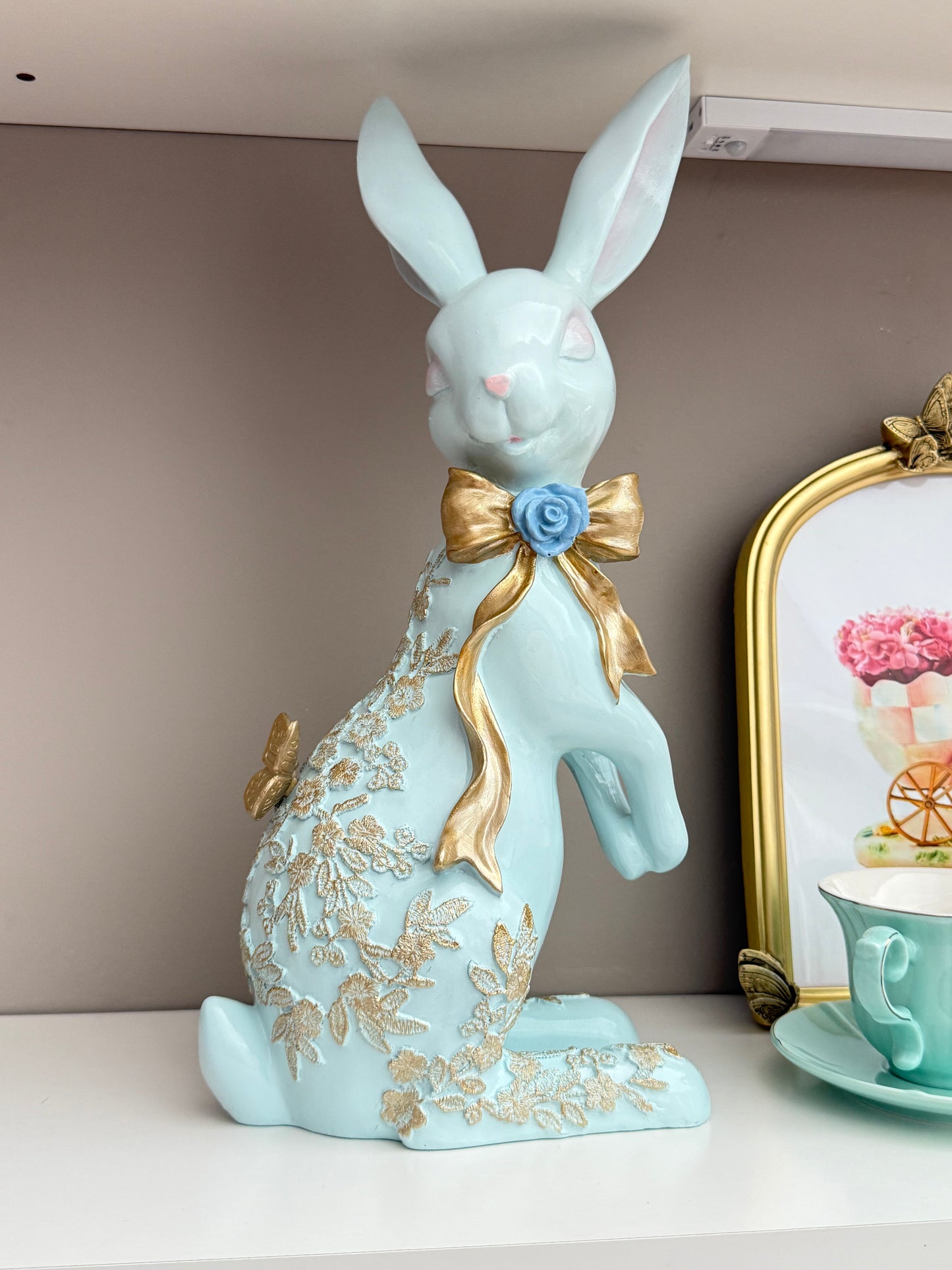 blue Easter spring bunny figurine with a gold bow and butterfly details.