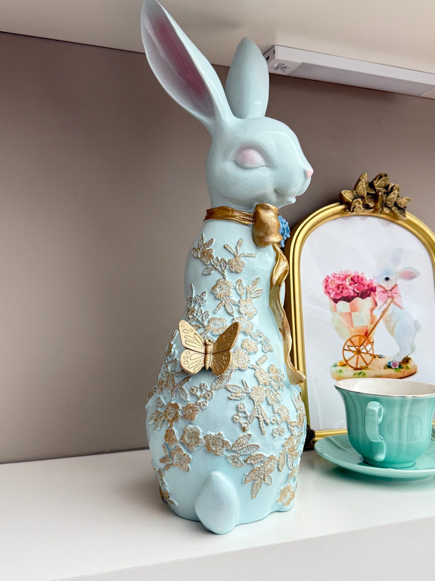 blue Easter spring bunny figurine with a gold bow and butterfly details.